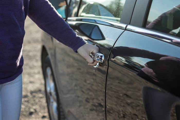 Kvinde rækker ud efter dørhåndtaget til bilen